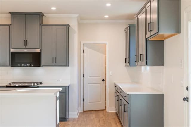 kitchen featuring gray cabinets, stainless steel stove, decorative backsplash, ornamental molding, and light wood-type flooring