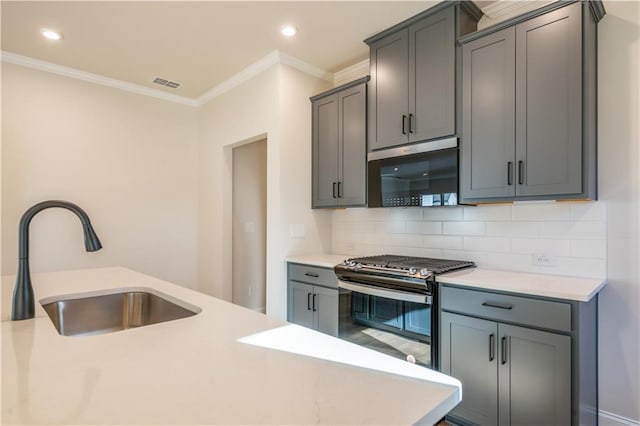 kitchen featuring appliances with stainless steel finishes, sink, gray cabinetry, backsplash, and ornamental molding