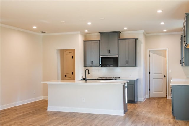 kitchen featuring stainless steel appliances, an island with sink, gray cabinets, and decorative backsplash