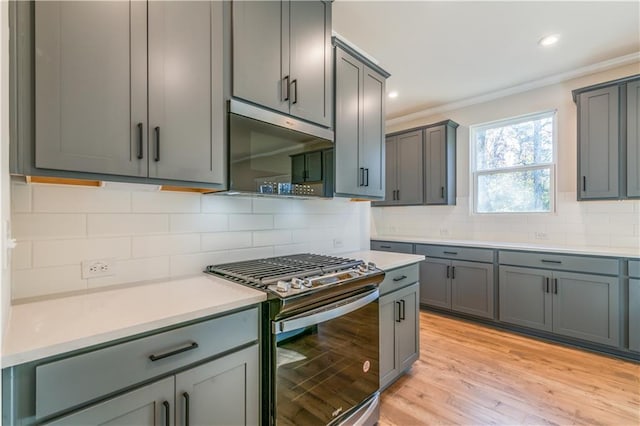 kitchen featuring gray cabinets, stainless steel appliances, tasteful backsplash, ornamental molding, and light wood-type flooring