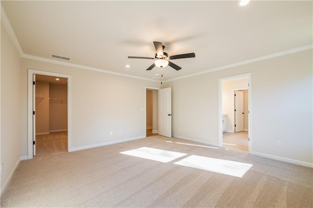 unfurnished bedroom featuring crown molding, a walk in closet, and light colored carpet