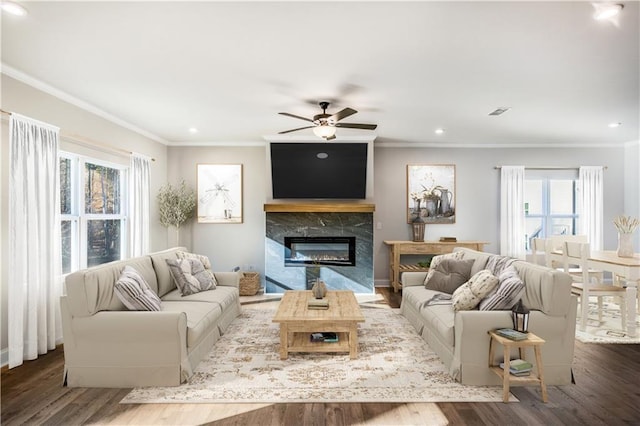 living room with hardwood / wood-style flooring, ornamental molding, ceiling fan, and a fireplace