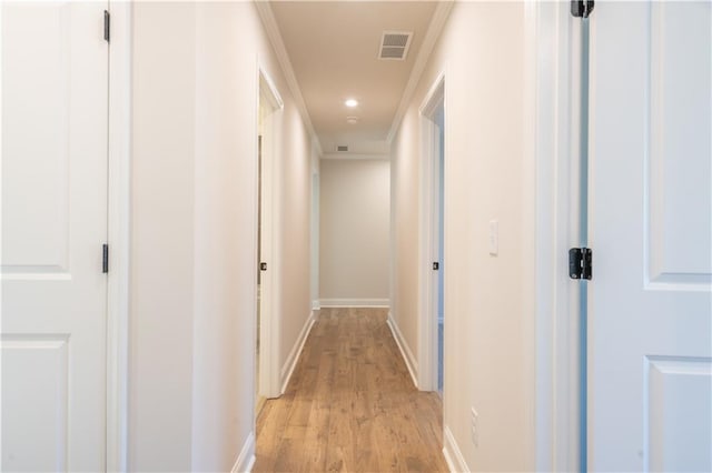 corridor with ornamental molding and light hardwood / wood-style floors