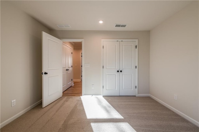 unfurnished bedroom featuring light carpet and a closet