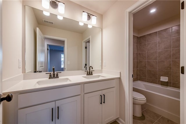 full bathroom featuring tiled shower / bath, tile patterned floors, toilet, and vanity