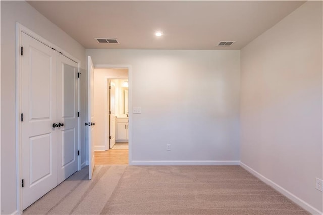 unfurnished bedroom featuring light colored carpet and a closet