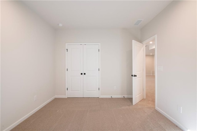 unfurnished bedroom with light carpet and a closet