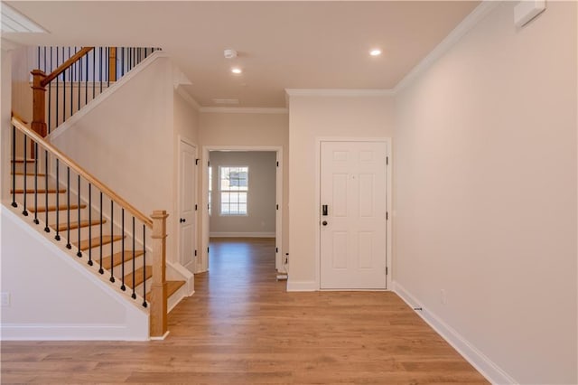 entryway with ornamental molding and light hardwood / wood-style floors