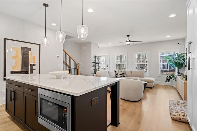 kitchen featuring light wood-type flooring, stainless steel microwave, and recessed lighting