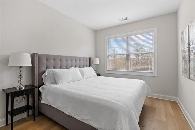 bedroom featuring baseboards, visible vents, and light wood finished floors