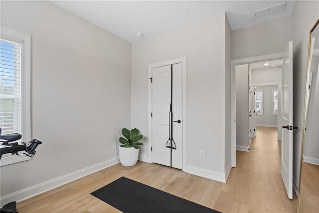 workout area with light wood-style flooring, visible vents, and baseboards