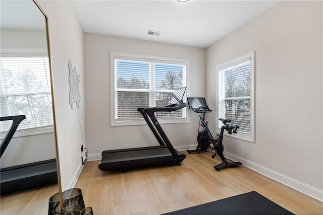 workout area featuring visible vents, light wood-type flooring, and baseboards