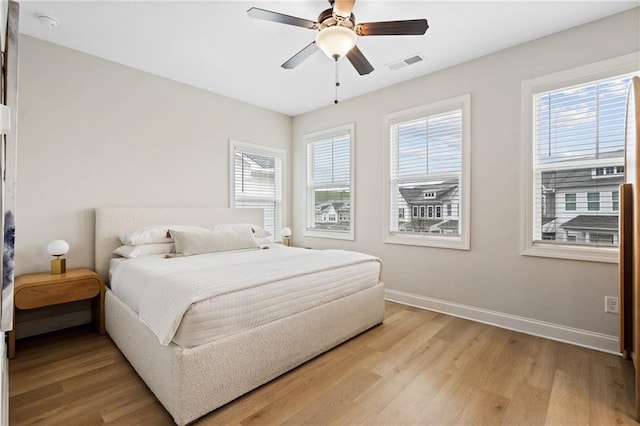 bedroom featuring a ceiling fan, light wood-style flooring, baseboards, and visible vents