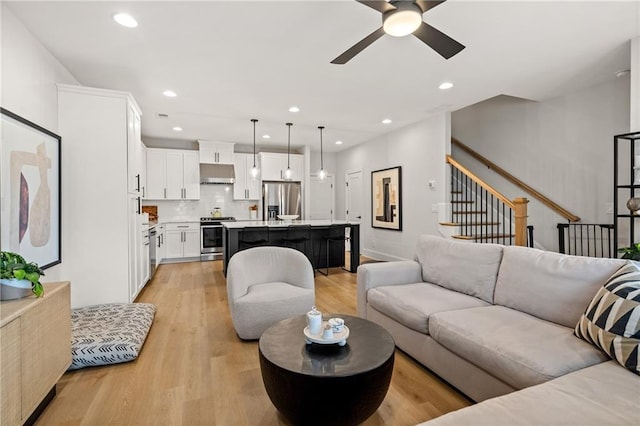 living area featuring light wood finished floors, stairway, recessed lighting, and a ceiling fan