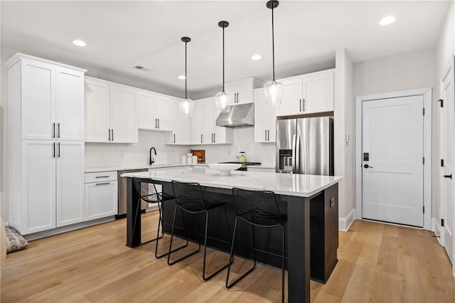 kitchen with under cabinet range hood, appliances with stainless steel finishes, white cabinetry, and a kitchen breakfast bar