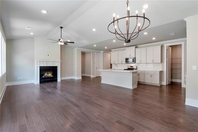 kitchen with appliances with stainless steel finishes, white cabinetry, sink, backsplash, and a center island with sink