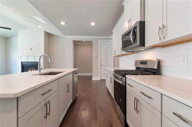 kitchen featuring sink, hanging light fixtures, stainless steel dishwasher, light stone countertops, and a center island with sink