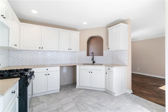 kitchen featuring gas range, decorative backsplash, recessed lighting, white cabinets, and a sink