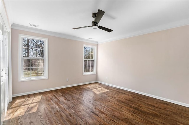 empty room featuring visible vents, a healthy amount of sunlight, crown molding, and dark wood-style flooring