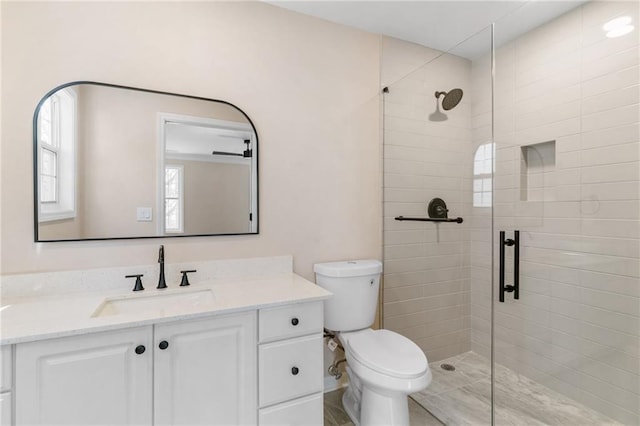 full bathroom with a tile shower, toilet, and vanity