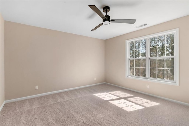 carpeted empty room featuring visible vents, a ceiling fan, and baseboards