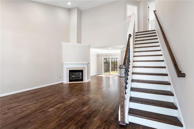 stairs with recessed lighting, a fireplace with flush hearth, wood finished floors, and baseboards