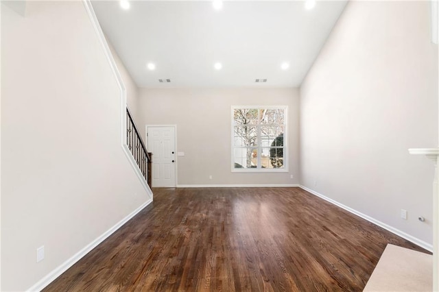 unfurnished living room featuring visible vents, stairway, dark wood-type flooring, and baseboards