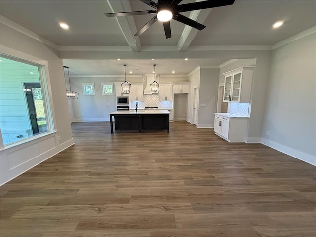 kitchen featuring white cabinets, dark hardwood / wood-style flooring, decorative light fixtures, and an island with sink