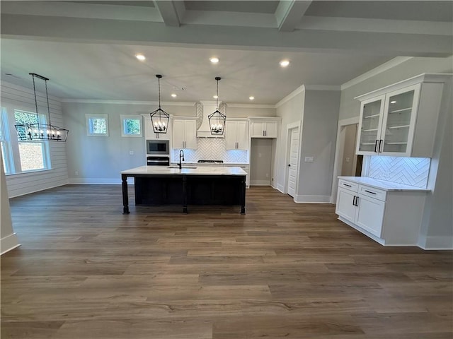 kitchen with a center island with sink, decorative backsplash, white cabinets, and appliances with stainless steel finishes