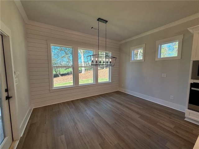 unfurnished dining area with crown molding, wood walls, dark hardwood / wood-style floors, and an inviting chandelier