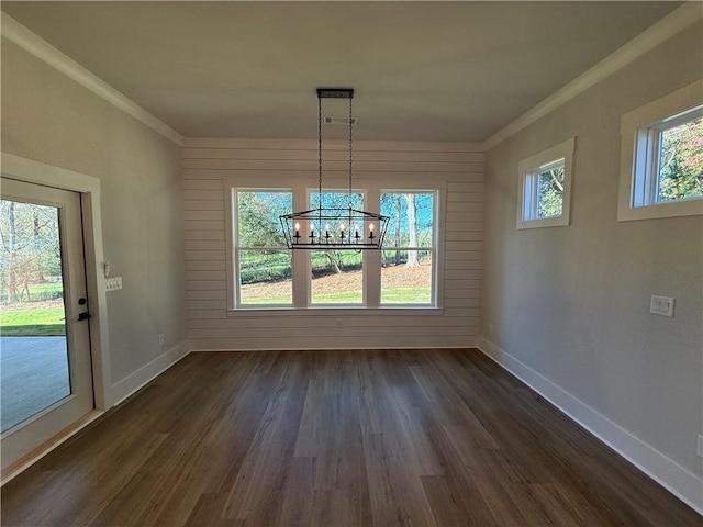 unfurnished dining area featuring crown molding, dark hardwood / wood-style flooring, and a chandelier