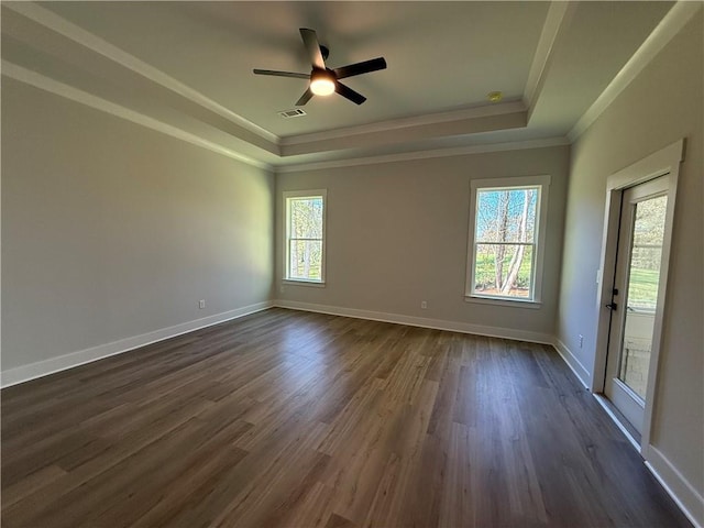 empty room with a tray ceiling, dark hardwood / wood-style floors, crown molding, and ceiling fan