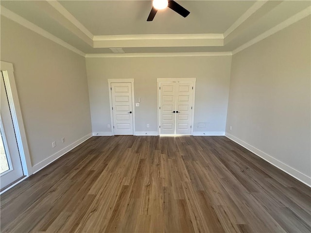 unfurnished bedroom with ceiling fan, a raised ceiling, and dark wood-type flooring