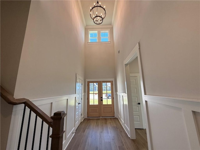 foyer entrance featuring a chandelier, wood-type flooring, crown molding, and french doors