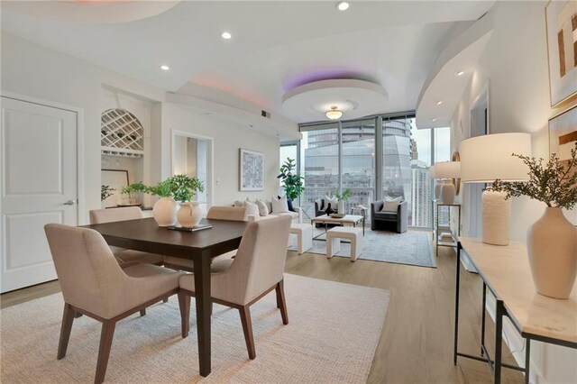 dining room with a wall of windows and light hardwood / wood-style floors