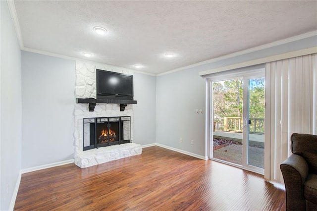 living room featuring wood-type flooring, crown molding, a textured ceiling, and a fireplace