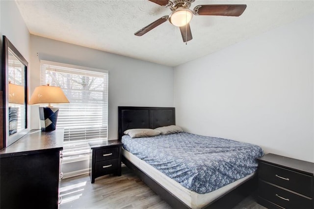 bedroom featuring ceiling fan, wood-type flooring, and a textured ceiling