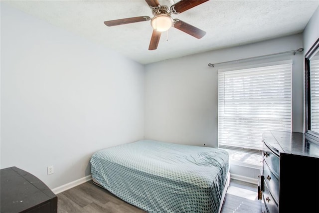 bedroom featuring dark wood-type flooring, ceiling fan, multiple windows, and a textured ceiling