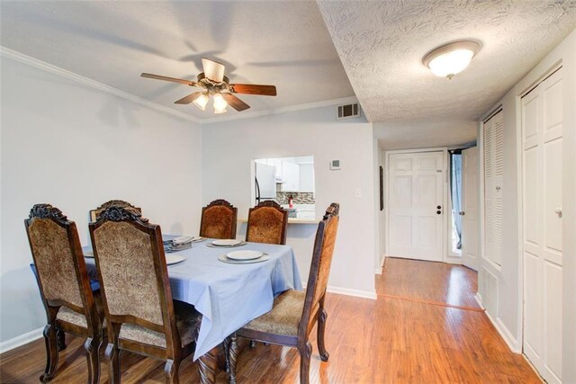 dining area with ceiling fan, ornamental molding, light hardwood / wood-style floors, and a textured ceiling