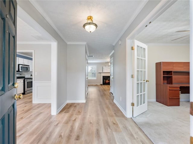 corridor featuring a textured ceiling, ornamental molding, and light hardwood / wood-style floors