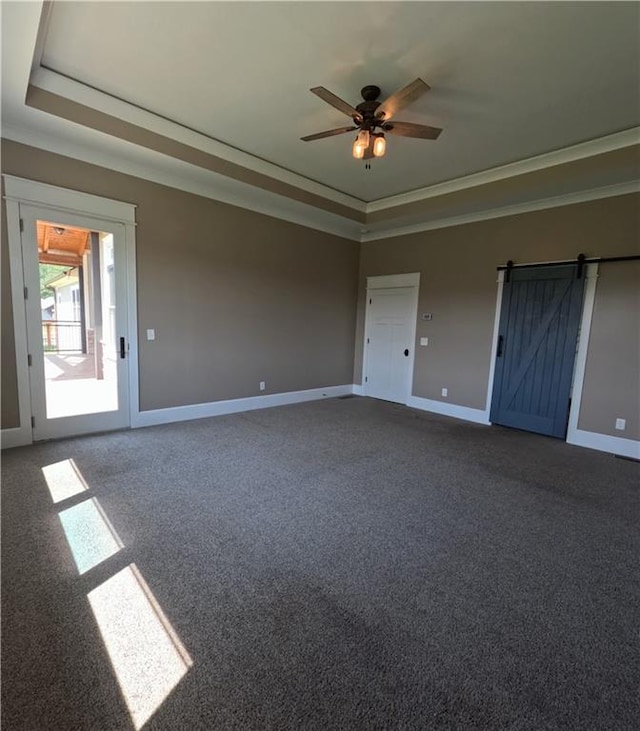 unfurnished bedroom with ceiling fan, a barn door, a raised ceiling, and carpet