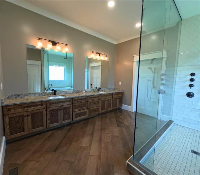 bathroom with an enclosed shower, double sink vanity, hardwood / wood-style flooring, and crown molding