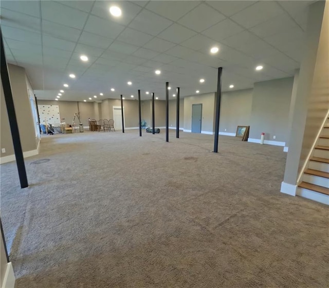 basement featuring a paneled ceiling and light carpet