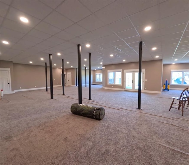 basement featuring a paneled ceiling and light carpet