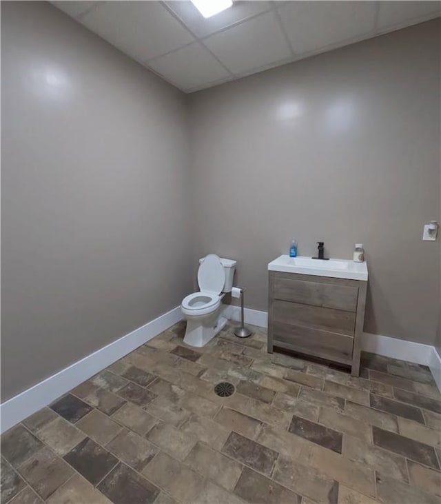 bathroom with a drop ceiling, vanity, tile patterned flooring, and toilet