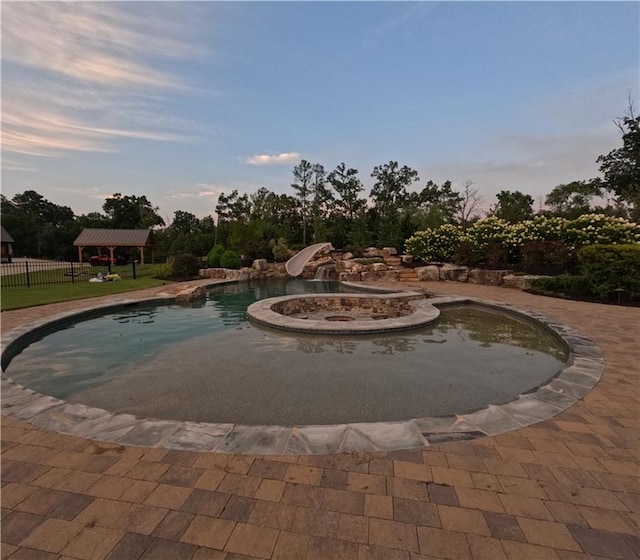 pool at dusk featuring a water slide