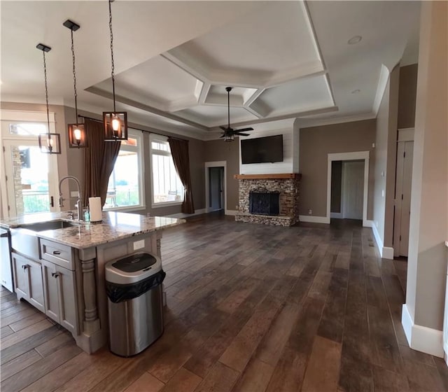 kitchen featuring coffered ceiling, hanging light fixtures, dark hardwood / wood-style floors, ceiling fan, and a fireplace