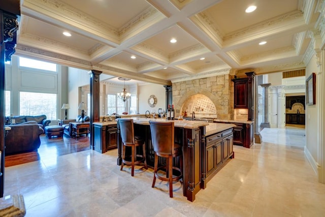 595 S Mount Carmel Rd, Mcdonough, GA 30253 - kitchen featuring decorative columns, a large island with sink, a kitchen bar, beamed ceiling, and a chandelier
