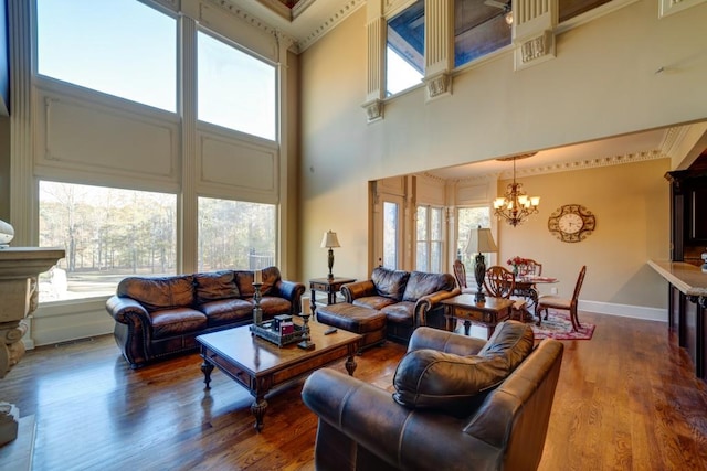 living room with hardwood / wood-style flooring, a towering ceiling, ornamental molding, and a notable chandelier