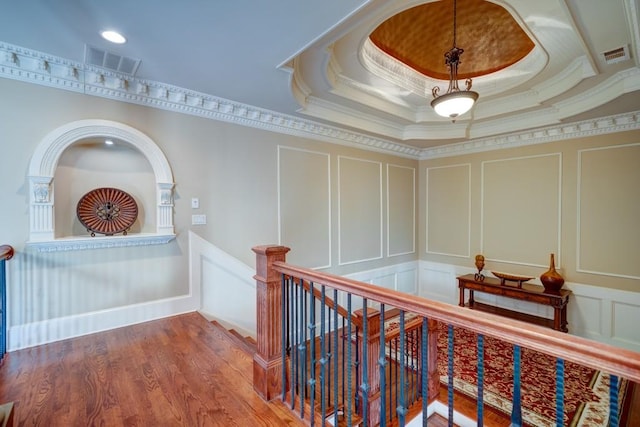 hall featuring a tray ceiling, crown molding, and wood-type flooring